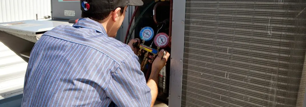 HVAC technician servicing a condenser unit in Griffith